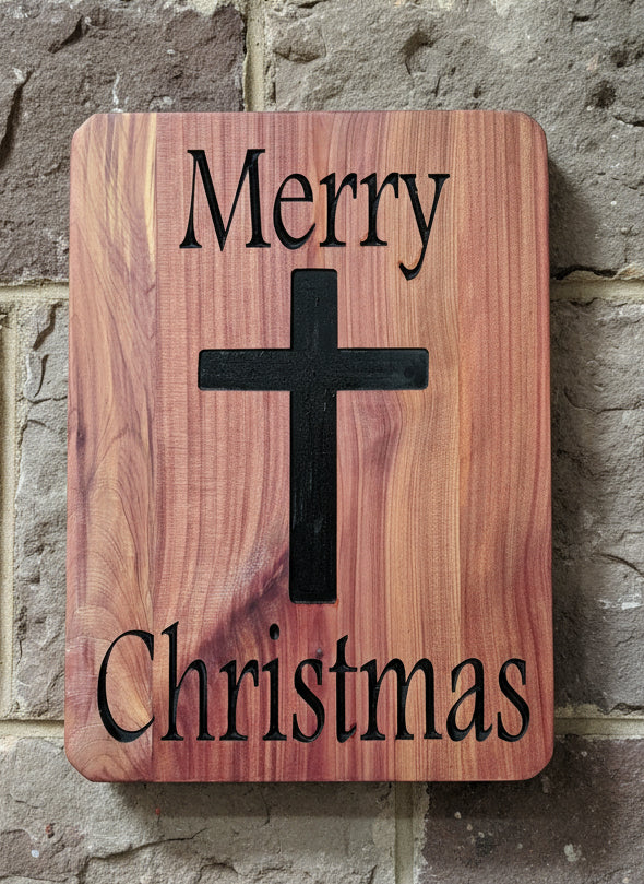 Wooden board with a black cross and 'Merry Christmas' text on a wooden background.